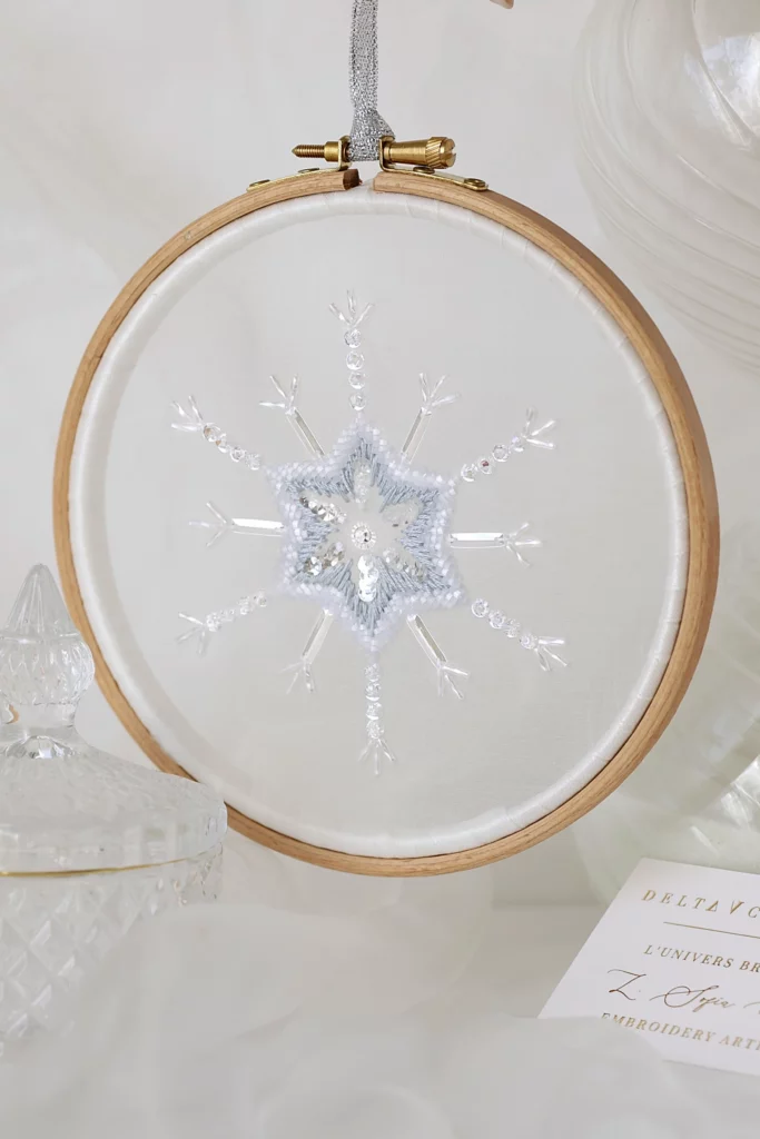 Un delicado copo de nieve bordado a mano, Bianca, expuesto en un entorno inspirado en el invierno, que captura la belleza cristalina de la naturaleza.