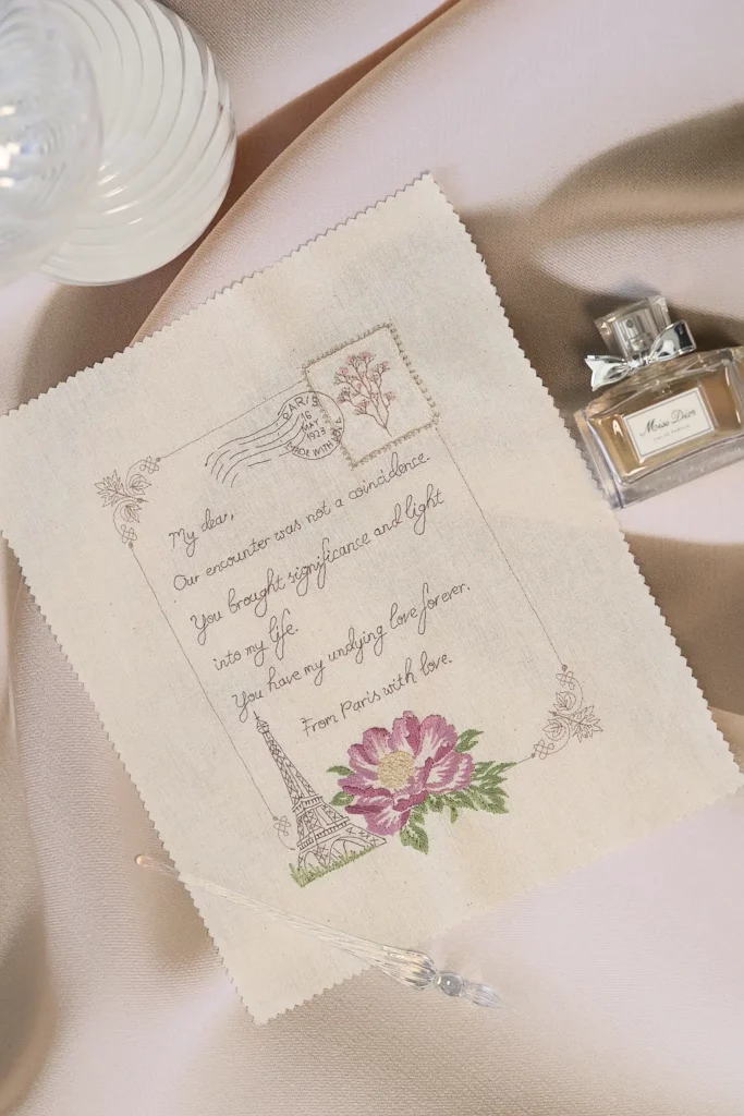 Una carta de amor bordada de estilo vintage con un sello parisino y la Torre Eiffel, que captura el romanticismo atemporal en delicadas puntadas.