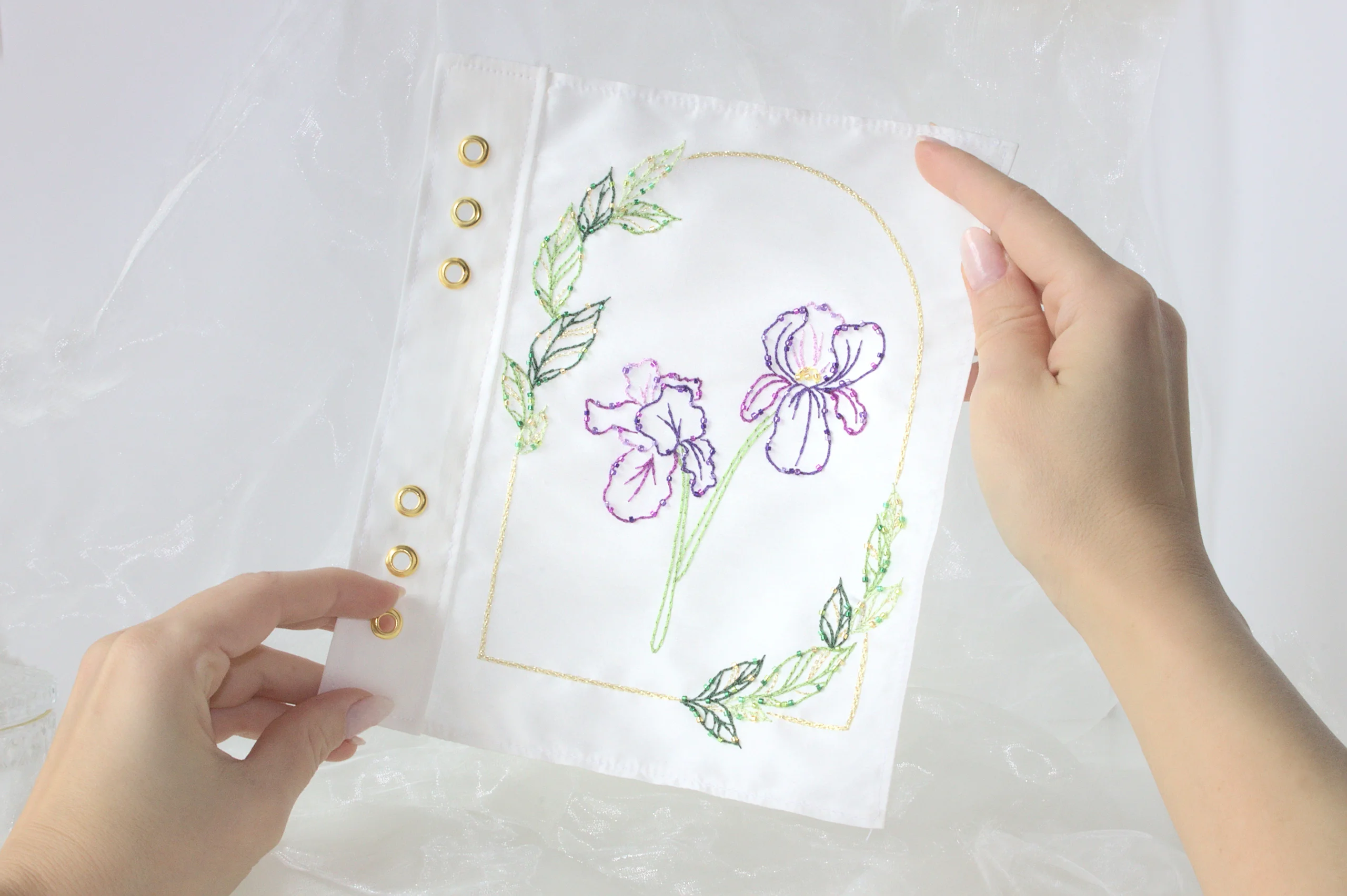 Haute Couture embroidery sample of an iris flower held between hands, showcasing the free embroidery model to download at Delta V Créations.