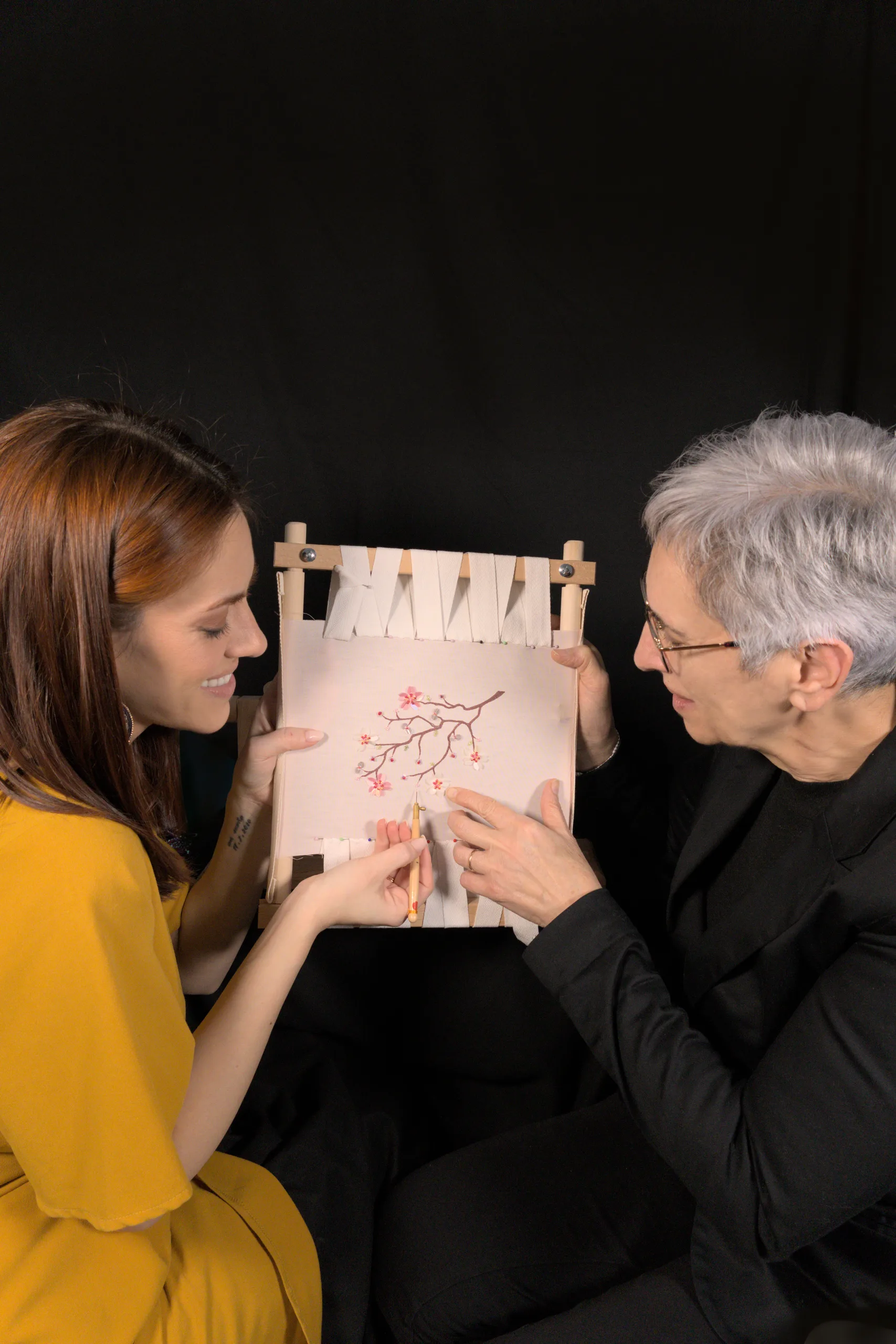 Embroidery instructor Laura S. Urbina demonstrating the Lunéville hook technique to a student during a hands-on Haute Couture embroidery workshop.