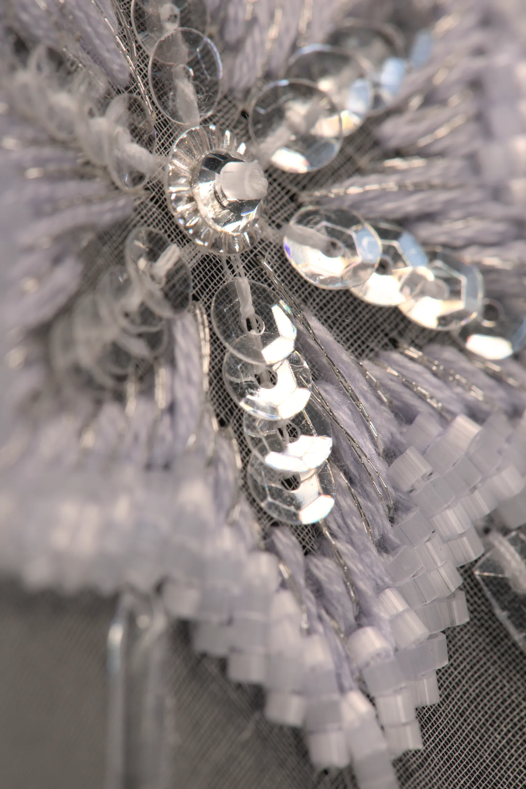 Macro shot of a refined snowflake embroidery pattern, showcasing delicate beadwork and Haute Couture craftsmanship.