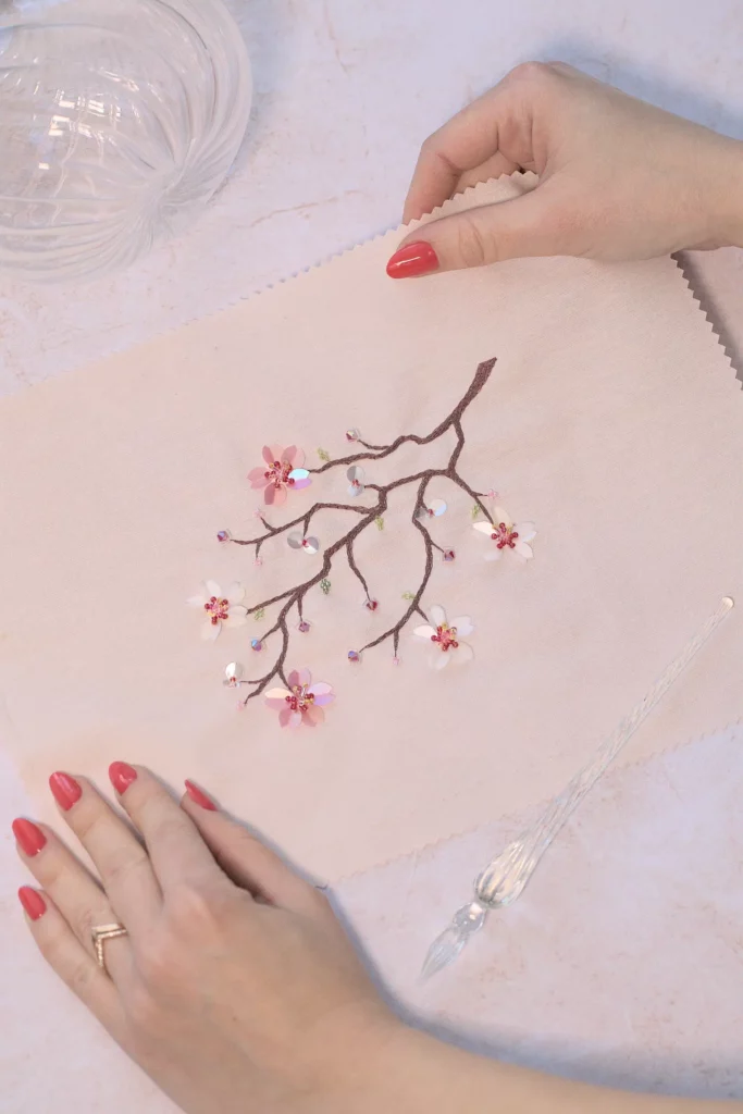 Diseño de bordado artesanal de flores de cerezo, Hoshi, sostenido en las manos, mostrando sus delicados detalles florales.