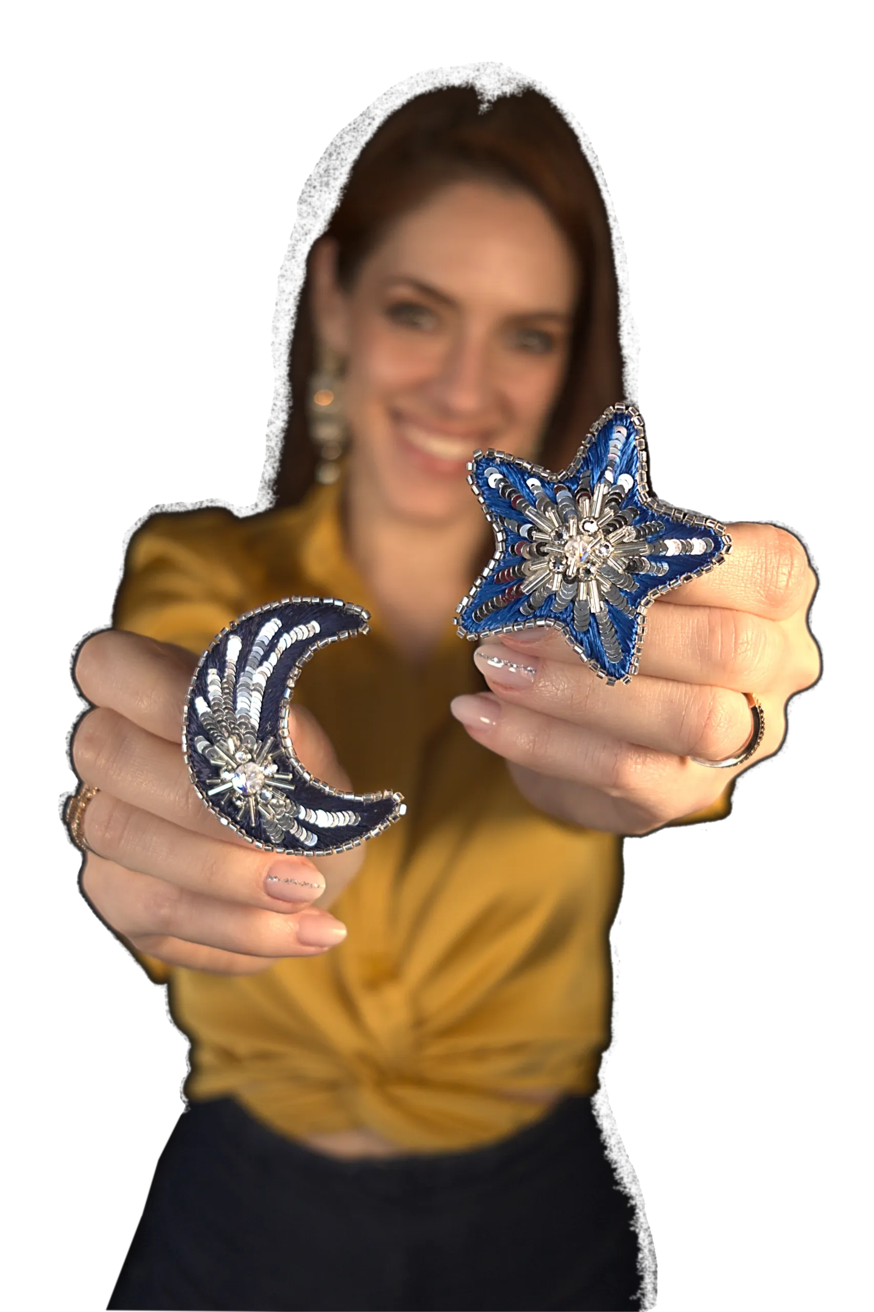 Portrait de Laura S. Urbina, artiste brodeuse, présentant deux broches en forme d'étoile et de lune réalisées à la main, symbolisant la créativité et l'expression artistique à travers l'art textile.
