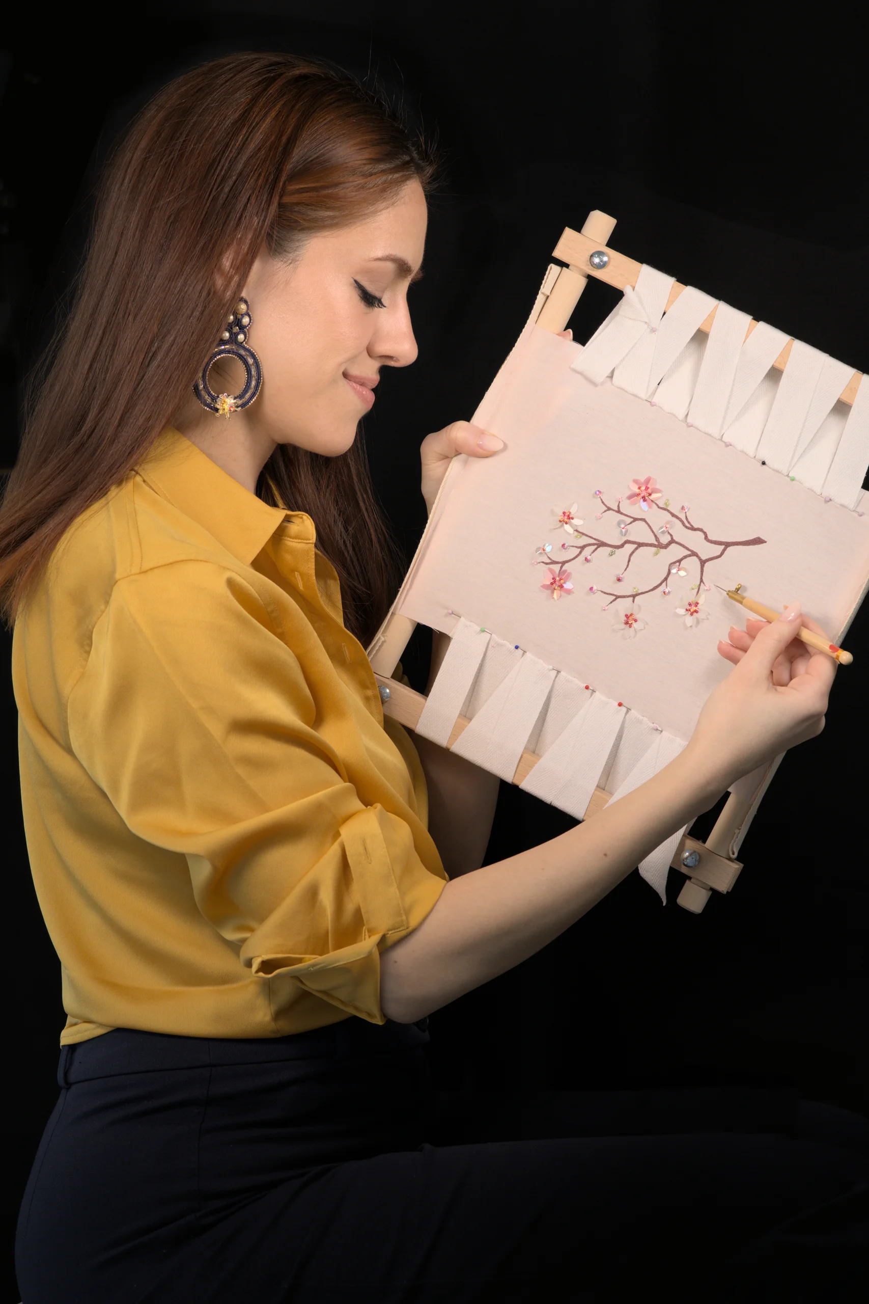 Laura S. Urbina demonstrating Haute Couture embroidery techniques on an embroidery frame during a hands-on workshop.