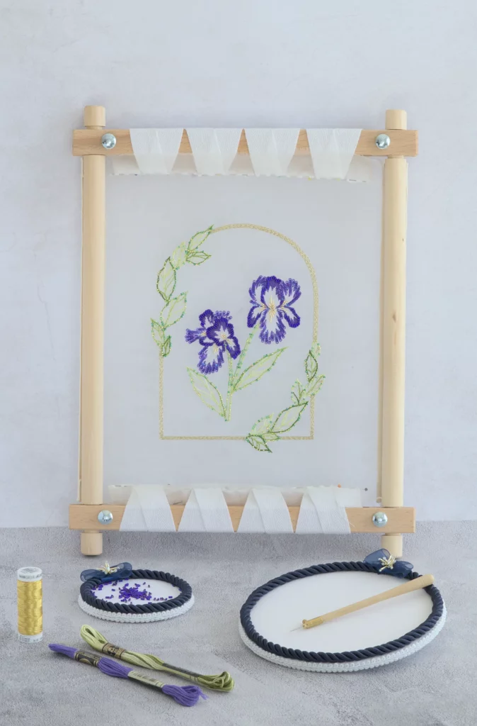 Vista del proyecto de bordado Nereid con flores de iris enmarcadas por hojas, bordado con el crochet de Lunéville.