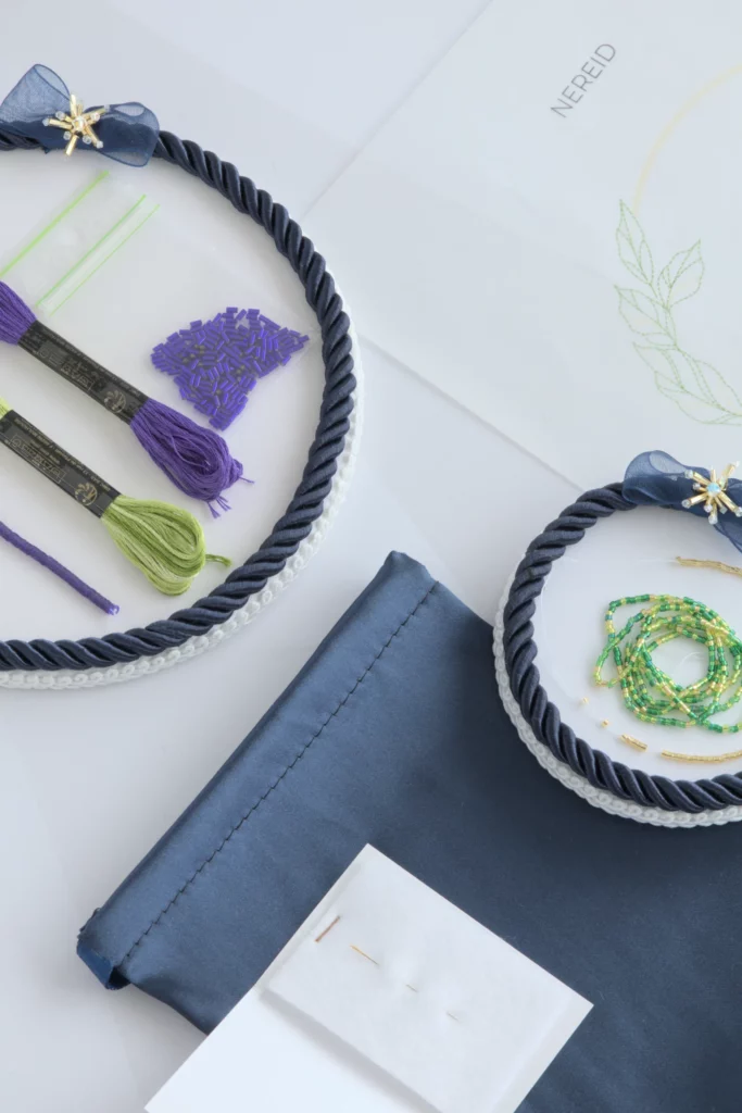 Embroidery kit for Nereid iris flower design with embroidery threads, green and gold beads, and supplies for Lunéville hook embroidery