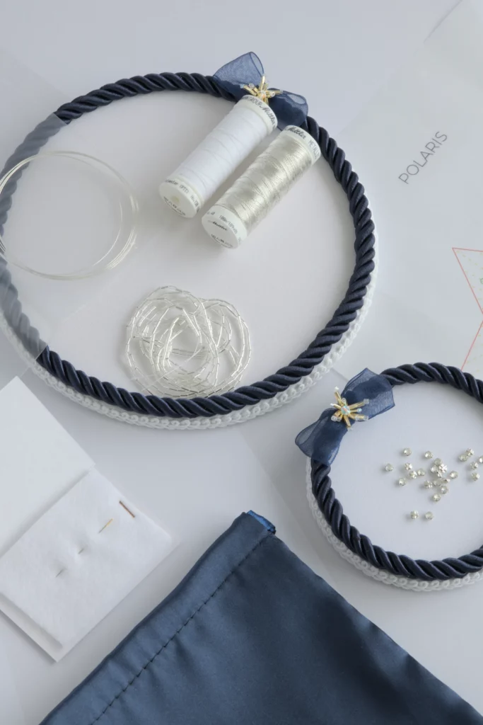 Flat lay of Polaris 3D Christmas star embroidery kit with threads, beads, and materials adapted to Lunéville hook embroidery.